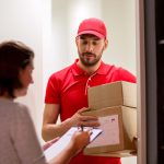 delivery, mail, people and shipping concept - man with clipboard delivering parcel boxes to customer signing form at home